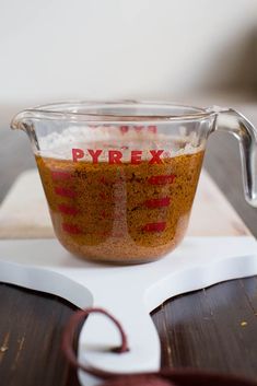 a measuring cup filled with spices on top of a wooden table