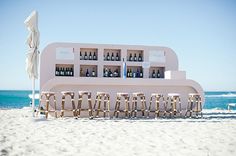 an empty bar on the beach with chairs and umbrellas