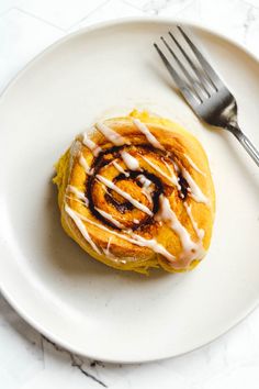 a white plate topped with a pastry covered in icing