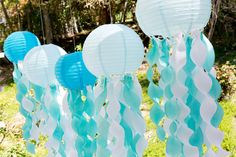 several blue and white paper lanterns hanging in the grass