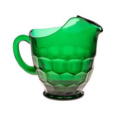 a green glass pitcher sitting on top of a table