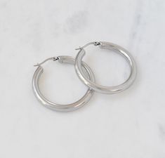 "SILVER MEDIUM CHUNKY HOLLOW HOOP EARRINGS Extremely lightweight, but oh so durable! These chunky silver hoops are a must have staple! Polished to perfection, these hoops will immediately add chicness to your look, day or night! Also available in gold Materials: Stainless steel Measurements: Outer diameter 1.625\", inner diameter 1.188\" . Hoop thickness 4mm Closure: Latch back Additional Info:  Hypoallergenic High Polish Eco-friendly: We use sustainable metals Tarnish resistant and waterproof" Silver Hoops Aesthetic, Hoops Aesthetic, Drippy Fits, Celine Earrings, Future Nostalgia, 10 Dinner, Thick Hoop Earrings, Prom Jewelry, Concert Fits