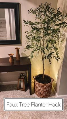 a fake tree in a basket next to a table with candles and a mirror on it