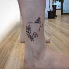 a person with a cow tattoo on their foot in the middle of a wooden floor