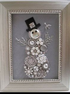 a snowman made out of buttons and other things in a silver frame on a table