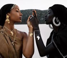 two women standing next to each other with jewelry on their hands and one is touching the other's face