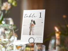 a table number with a photo on it next to some wine glasses and other items