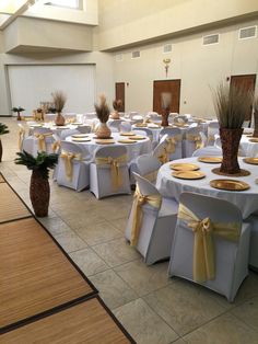 a banquet hall with tables and chairs covered in white linens, decorated with pineapple centerpieces