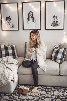 a woman sitting on top of a couch holding a cup