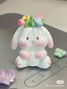 a ceramic bunny sitting on top of a table next to some plastic butterflies and flowers