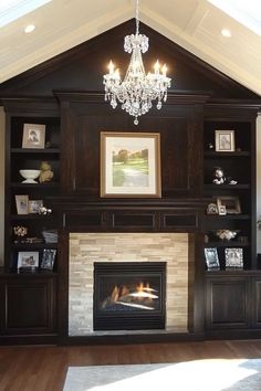 a living room with a fire place in the center and a chandelier hanging from the ceiling