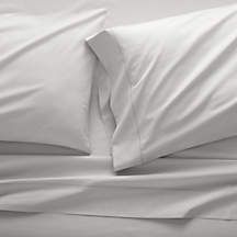 an unmade bed with white sheets and pillows