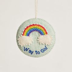 a felt ornament with a rainbow and clouds hanging from it's side