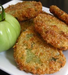 some fried food on a white plate with a green apple next to it and an orange