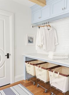 an organized closet with clothes hanging on hooks and storage bins under the counter top