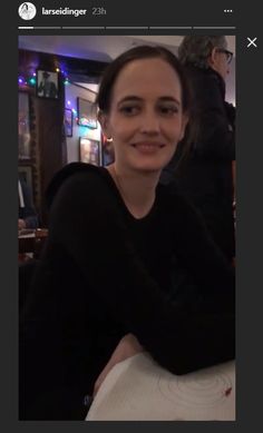 a woman sitting at a table smiling for the camera