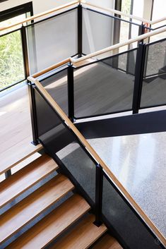 a stair case with glass railing and wood handrail