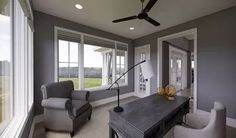 a living room with two chairs and a table in front of large windows that look out onto an open field