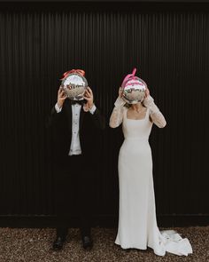 two people wearing masks standing next to each other with their faces covered by paper plates