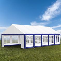 a large white and blue tent in the middle of a field with windows on it