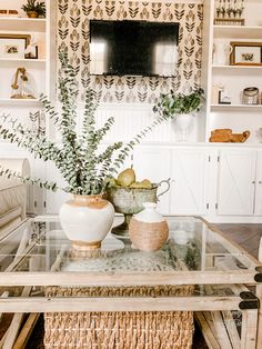 a glass table with two vases sitting on top of it in front of a tv