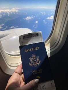 a person holding up a passport in front of an airplane window