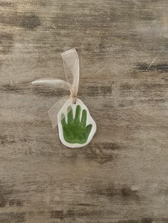 an ornament shaped like a hand with green leaves in it on a wooden surface