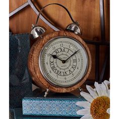 an alarm clock sitting on top of a stack of books next to a white flower