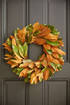 a wreath is hanging on a door with green and orange leaves in the shape of a leaf