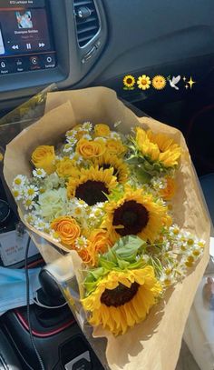 sunflowers and daisies are in a bouquet on the dashboard of a car