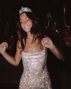 a woman wearing a tiara and smiling at the camera with her hands in the air