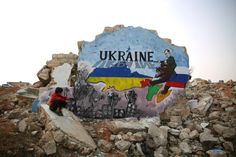 there is a man sitting on the rocks next to a large sign that says ukraine