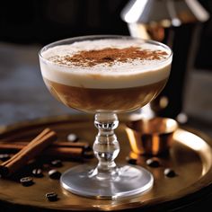 a glass filled with liquid sitting on top of a wooden table next to cinnamons