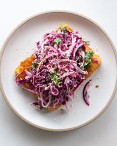 a white plate topped with a piece of bread covered in coleslaw