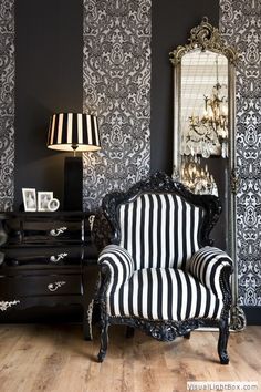 a black and white striped chair sitting in front of a mirror on top of a wooden floor