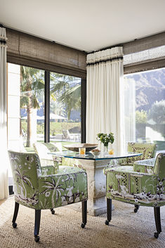 a living room with two chairs and a table in front of a large glass window