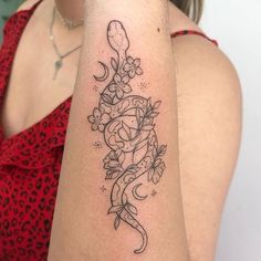 a woman's arm with a tattoo on it that has flowers and a snake