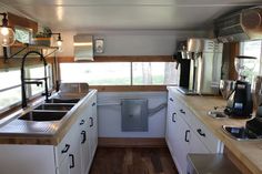 a kitchen area with sink, stove and microwave inside of a mobile home that has wood flooring