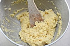 a metal bowl filled with yellow batter and a wooden spoon in the bottom right corner