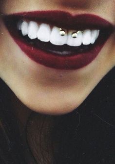 a close up of a woman's mouth with teeth and piercings on it