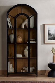 An Image of the 4 -Tier Modern Standing Arched Display Cabinet with Glass Doors against a white painted wall, beside a wall photo and a small vase. Bedroom Glass Cabinet, Cabinet For Study Room, Display Cabinet Ideas, Bookshelf With Glass Doors, Arched Display Cabinet, Arch Bookcase, Modern Display Cabinet, House Accents, Display Cabinet Modern