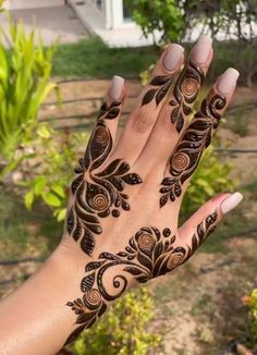 a woman's hand with hennap on it, and some plants in the background