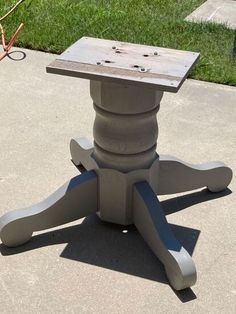 a small wooden table sitting on top of a cement floor next to a grass field