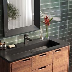 a bathroom sink with a mirror above it and a vase filled with flowers on the counter