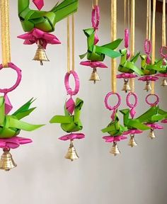 the bells are decorated with pink and green paper flowers hanging from gold colored cords,