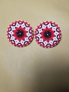 two red and white beaded circles on a tan surface, one with black center