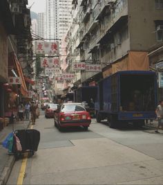 a busy street with cars and people walking on the sidewalk in front of tall buildings