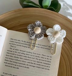 two crocheted flower book clips sitting on top of an open book