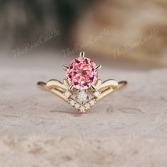 a close up of a ring with a pink stone in the center and two diamonds on each side