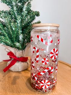 a jar filled with candy canes sitting on top of a table next to a christmas tree